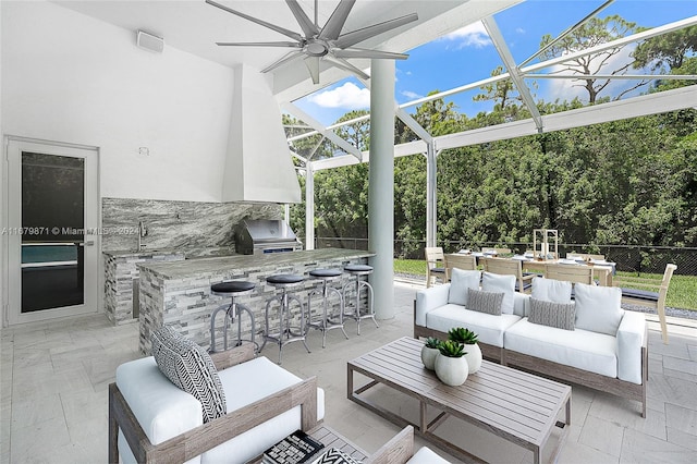 view of patio featuring area for grilling, an outdoor wet bar, grilling area, ceiling fan, and an outdoor living space