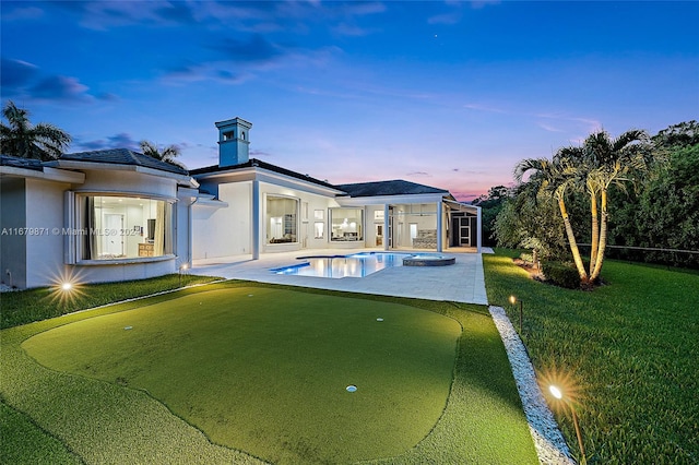 pool at dusk featuring a yard and a patio