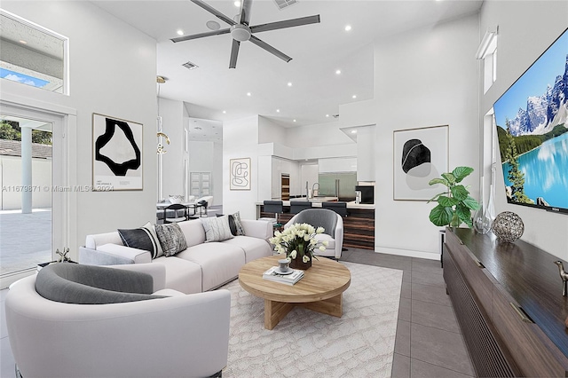 living room with a towering ceiling, ceiling fan, and tile patterned flooring