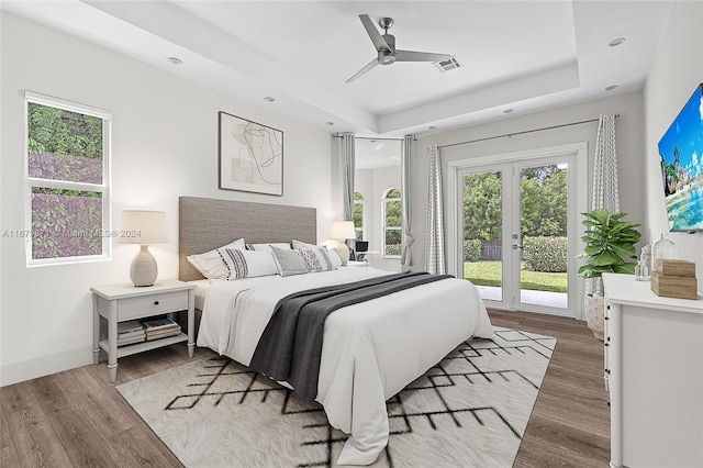 bedroom featuring ceiling fan, a raised ceiling, access to outside, and light hardwood / wood-style flooring