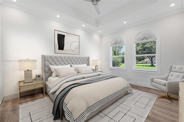 bedroom with ornamental molding, a tray ceiling, light hardwood / wood-style floors, and ceiling fan