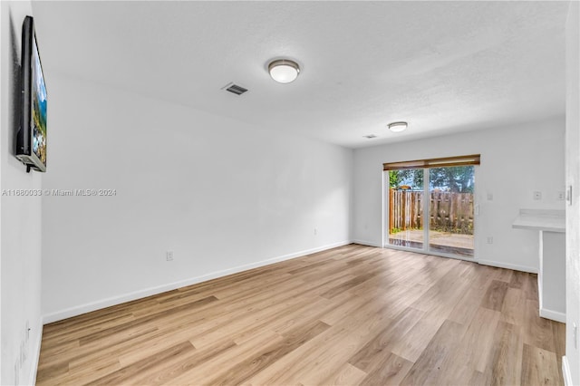 spare room with light hardwood / wood-style flooring and a textured ceiling