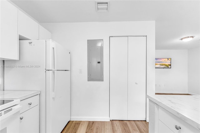 kitchen featuring light stone countertops, light wood-type flooring, white refrigerator, electric panel, and white cabinets