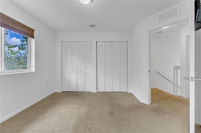 unfurnished bedroom with light carpet and two closets