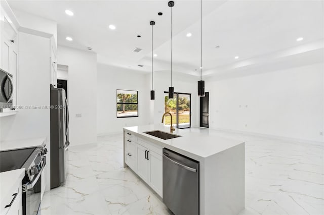 kitchen with sink, appliances with stainless steel finishes, pendant lighting, a kitchen island with sink, and white cabinets