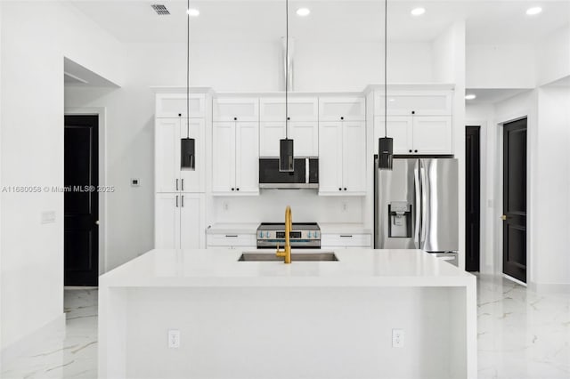 kitchen with white cabinetry, stainless steel appliances, an island with sink, and hanging light fixtures