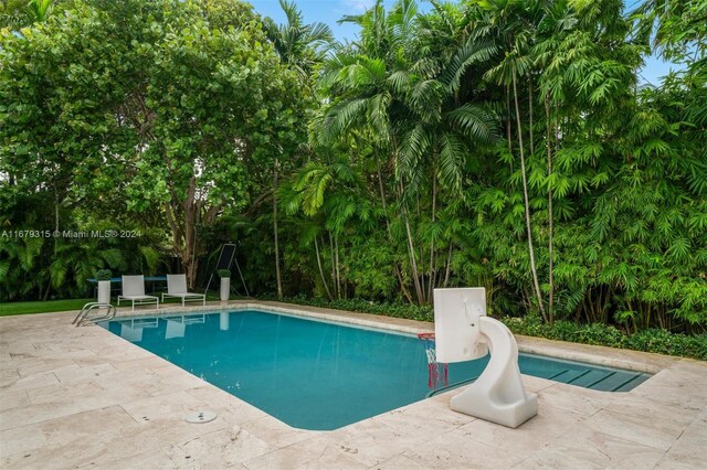 view of swimming pool featuring a water slide and a patio area