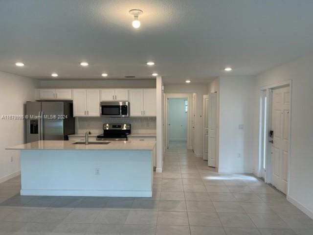 kitchen featuring decorative backsplash, a center island with sink, sink, white cabinets, and appliances with stainless steel finishes