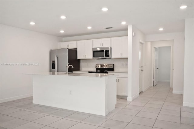 kitchen featuring sink, tasteful backsplash, appliances with stainless steel finishes, a kitchen island with sink, and white cabinets