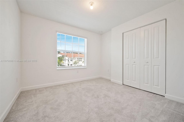 unfurnished bedroom with light colored carpet and a closet