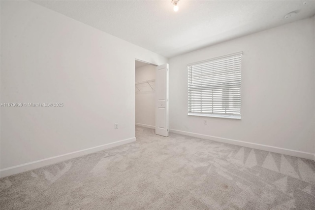 unfurnished bedroom featuring a walk in closet, light colored carpet, and a closet