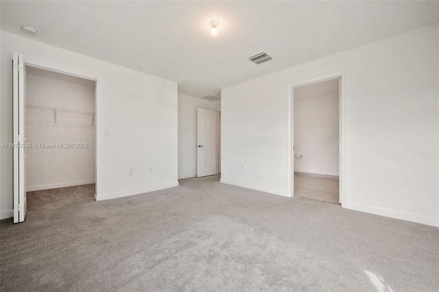 unfurnished bedroom with a spacious closet, carpet floors, and a closet