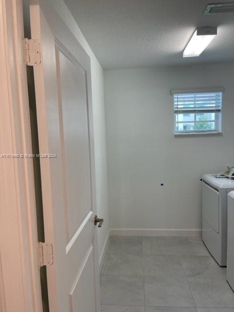 washroom with washer and clothes dryer and a textured ceiling