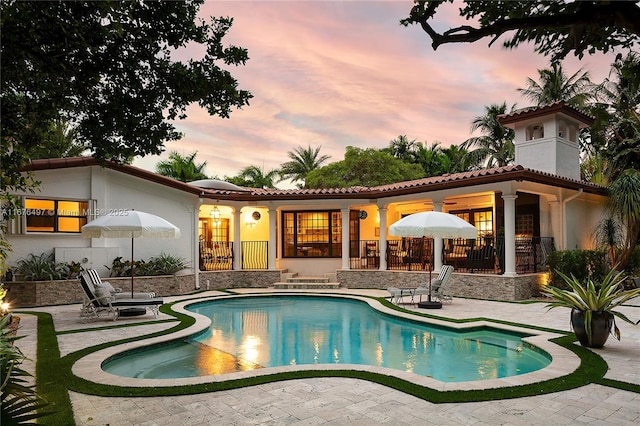 back house at dusk featuring a patio area