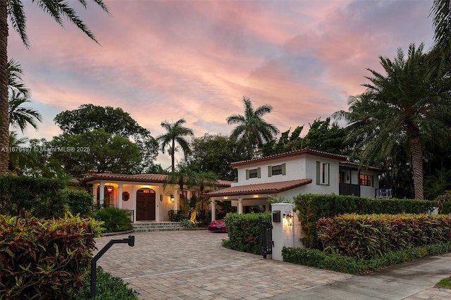 mediterranean / spanish house with a tiled roof, a gate, and stucco siding