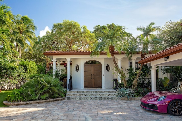 property entrance featuring covered porch, stucco siding, and a tiled roof