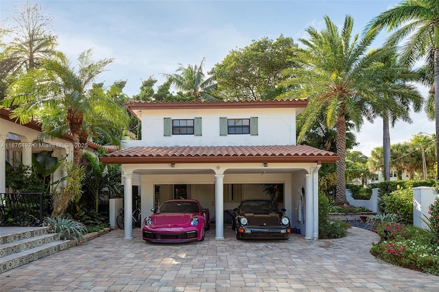 mediterranean / spanish house featuring stucco siding, a carport, driveway, and a tiled roof