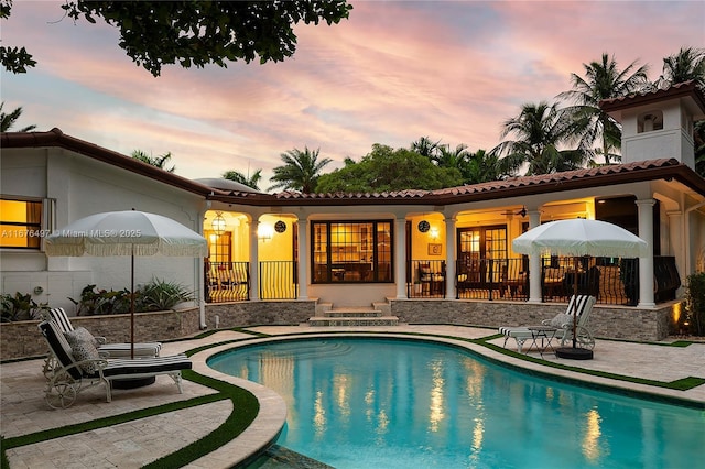 2616 Acacia Ct, Fort Lauderdale, FL 33301 - back of property at dusk featuring a patio, a tiled roof, an outdoor pool, and stucco siding