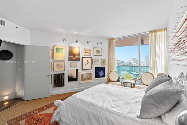 bedroom featuring hardwood / wood-style floors, access to exterior, and floor to ceiling windows