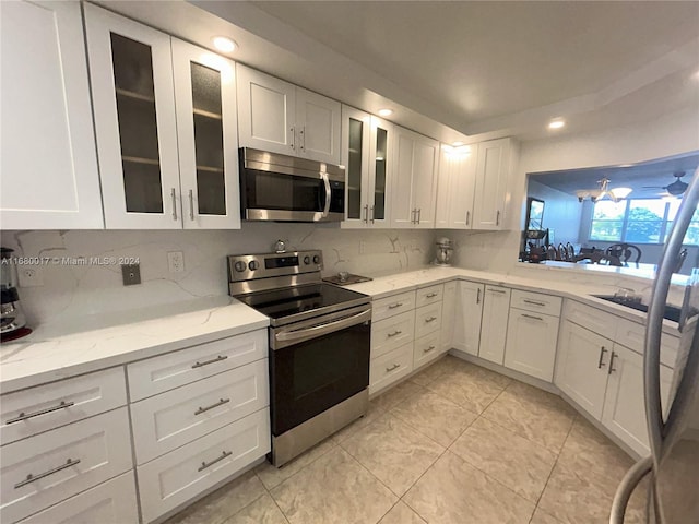 kitchen with light tile patterned flooring, white cabinetry, stainless steel appliances, light stone counters, and decorative backsplash