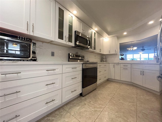 kitchen featuring backsplash, appliances with stainless steel finishes, white cabinetry, and light tile patterned flooring