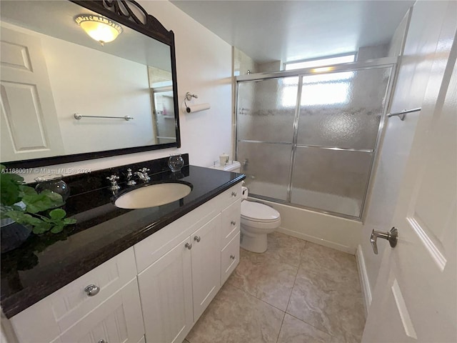 full bathroom with vanity, bath / shower combo with glass door, toilet, and tile patterned flooring