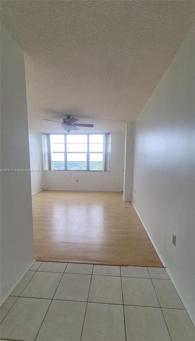 spare room with ceiling fan, light hardwood / wood-style floors, and a textured ceiling