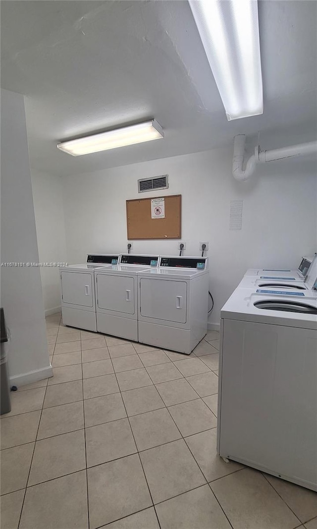 laundry area with washing machine and clothes dryer and light tile patterned floors