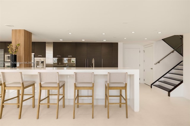55 Merrick Way Unit 808, Coral Gables, FL 33134 - kitchen with light countertops, a breakfast bar area, recessed lighting, modern cabinets, and a sink