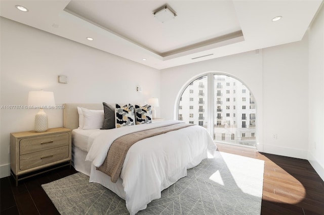 bedroom featuring a tray ceiling and dark wood-type flooring