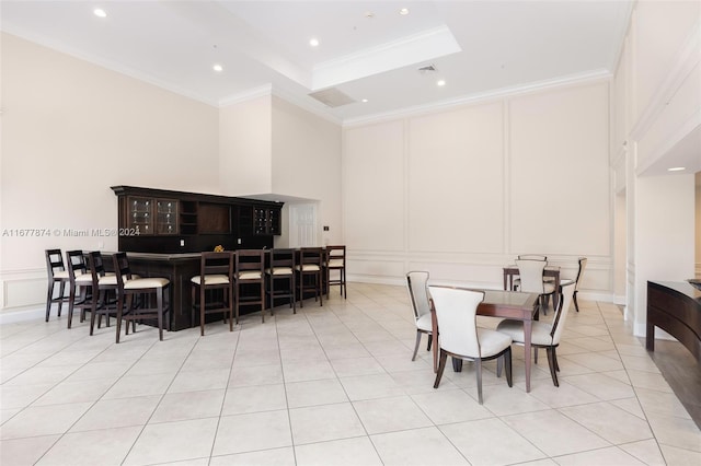 dining space with light tile patterned floors, indoor bar, and ornamental molding