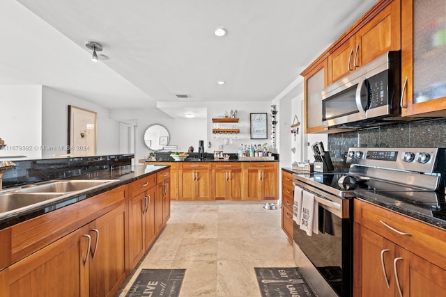 kitchen with sink, backsplash, stainless steel appliances, and dark stone counters