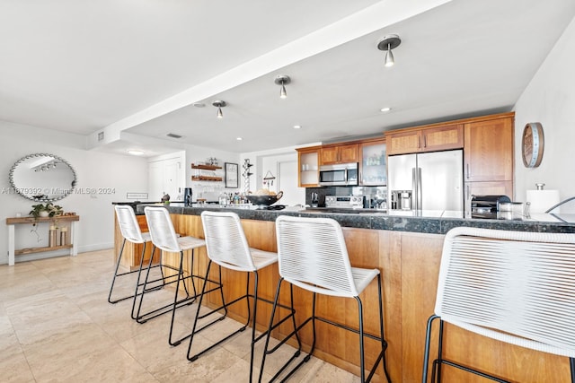 kitchen featuring a kitchen bar, kitchen peninsula, stainless steel appliances, and backsplash