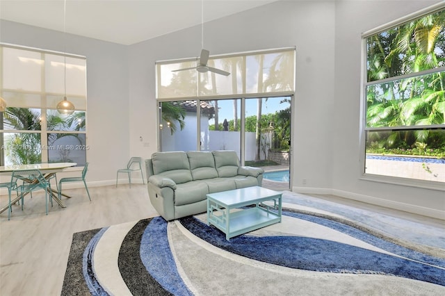 living room featuring ceiling fan, baseboards, plenty of natural light, and wood finished floors