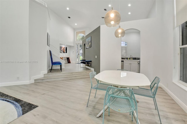 dining space featuring sink, a high ceiling, and light hardwood / wood-style flooring