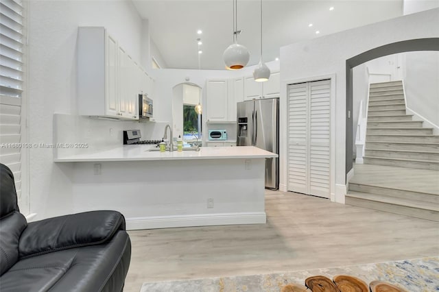 kitchen featuring kitchen peninsula, white cabinets, and decorative light fixtures