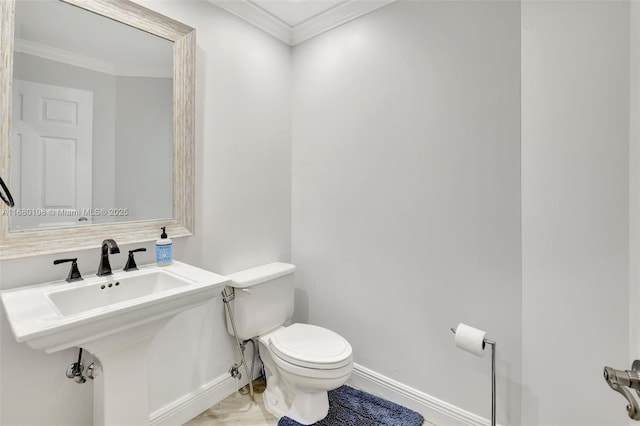 bathroom with toilet, ornamental molding, and sink