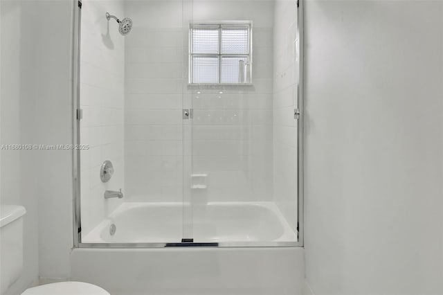 bathroom featuring toilet and shower / bath combination with glass door