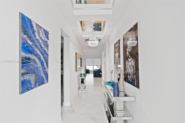 hallway with a tray ceiling and a notable chandelier