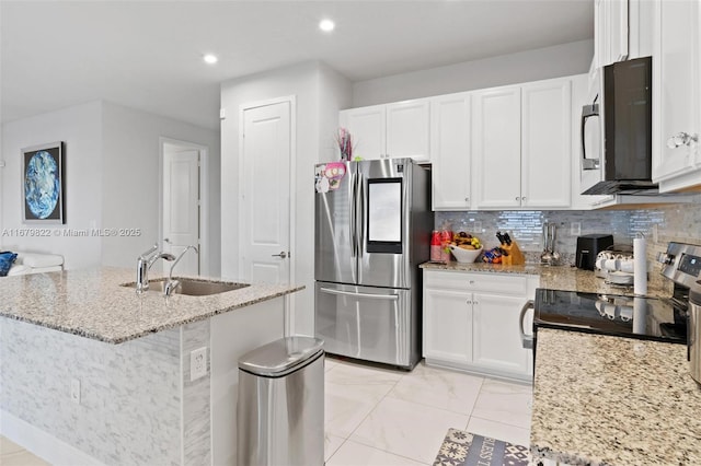 kitchen with white cabinetry, light stone counters, stainless steel appliances, and a center island with sink