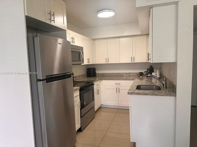 kitchen with stainless steel appliances, sink, light stone countertops, light tile patterned floors, and white cabinets