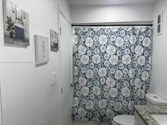 bathroom featuring vanity, toilet, and walk in shower