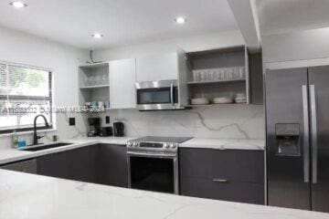 4384 SW 12th St, Miami, FL 33134 - kitchen with sink, light stone countertops, white cabinets, appliances with stainless steel finishes, and tasteful backsplash