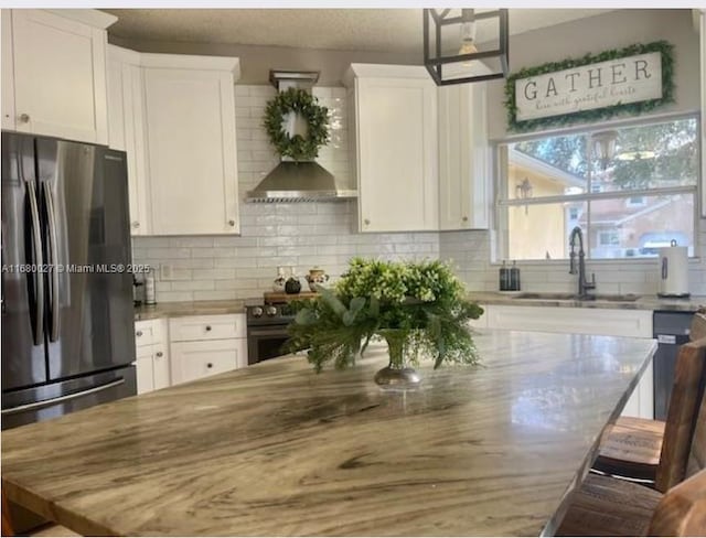 kitchen with appliances with stainless steel finishes, sink, white cabinets, backsplash, and light stone counters