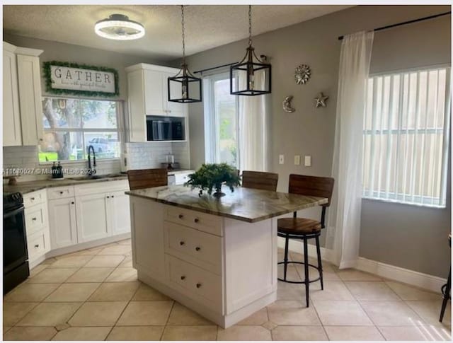 kitchen with a kitchen island, white cabinets, and range