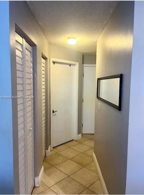 hallway featuring light tile patterned floors and a textured ceiling