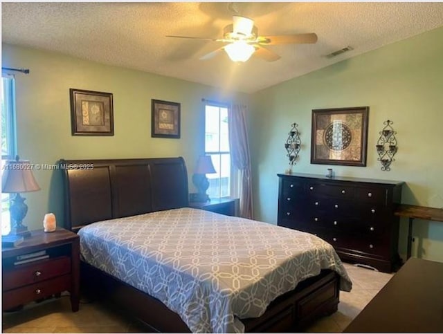 tiled bedroom with ceiling fan, a textured ceiling, and vaulted ceiling