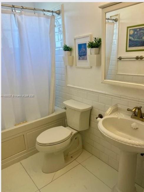 bathroom featuring shower / bath combo with shower curtain, toilet, tile patterned floors, and tile walls