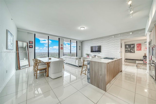 kitchen with light tile patterned flooring, a center island, expansive windows, stainless steel gas stovetop, and a breakfast bar area