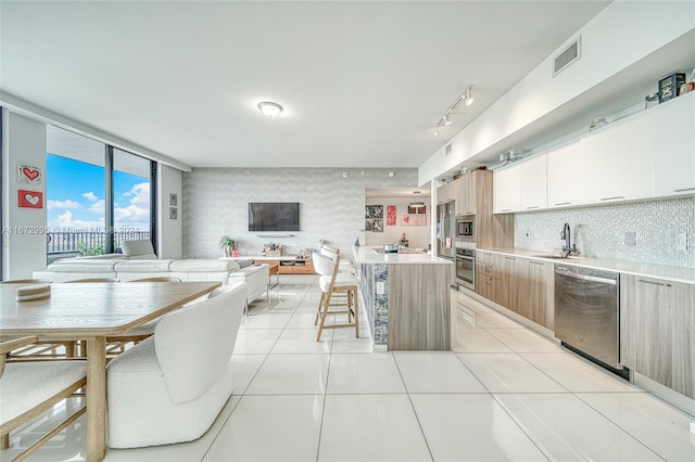 kitchen with white cabinets, tasteful backsplash, light tile patterned floors, sink, and stainless steel appliances